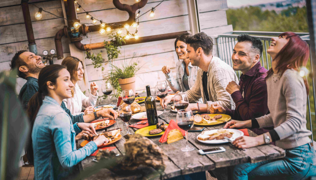 A group of people dining outside, drinking wine, and enjoying themselves