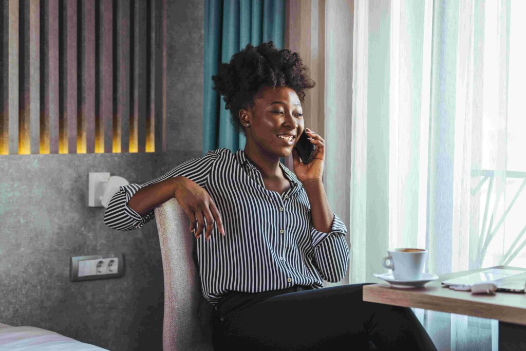 A professional woman smiling and drinking coffee as she talks on the phone